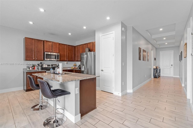 kitchen with a breakfast bar area, recessed lighting, appliances with stainless steel finishes, a kitchen island, and light wood-type flooring