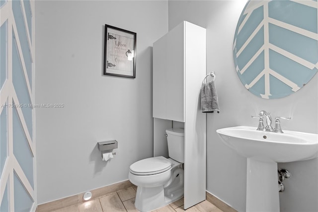 bathroom with baseboards, a sink, toilet, and tile patterned floors