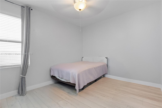 bedroom with light wood-style floors, a ceiling fan, and baseboards