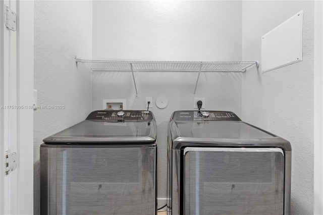 washroom with laundry area, a textured wall, and washer and clothes dryer