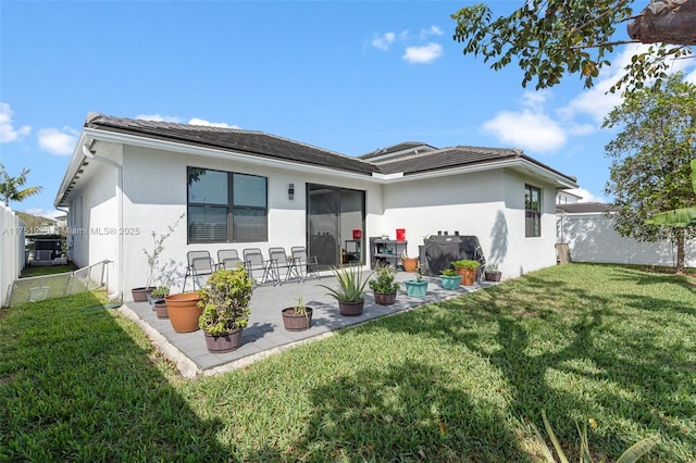 back of property featuring stucco siding, a lawn, fence, and a patio