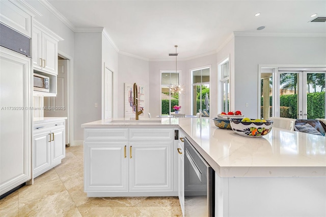 16721 SW 86th Ct, Palmetto Bay, FL 33157 - kitchen with built in appliances, crown molding, white cabinetry, light stone counters, and a large island with sink