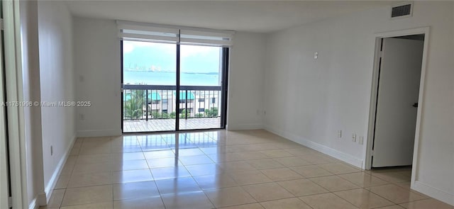 unfurnished room with light tile patterned floors, baseboards, floor to ceiling windows, and visible vents