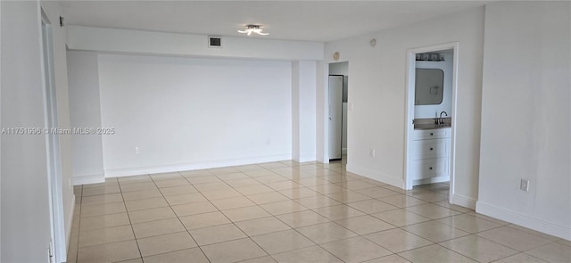 spare room featuring light tile patterned flooring, visible vents, and baseboards