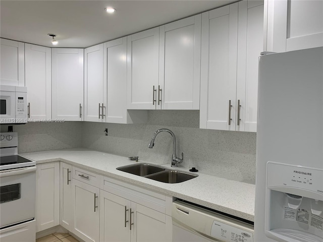 kitchen with white appliances, white cabinetry, and a sink