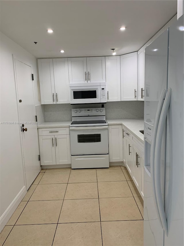 kitchen with white appliances, light tile patterned floors, white cabinetry, and light countertops