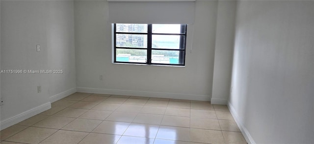 empty room with baseboards and light tile patterned floors