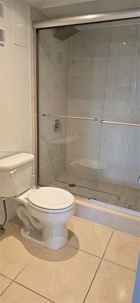 bathroom featuring toilet, a stall shower, and tile patterned floors