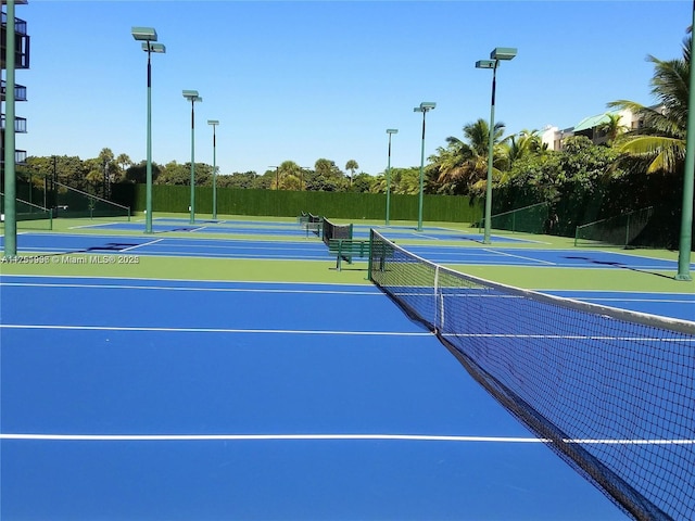 view of tennis court featuring community basketball court and fence