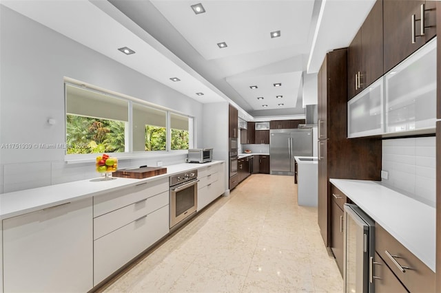 kitchen with beverage cooler, modern cabinets, stainless steel built in fridge, and tasteful backsplash