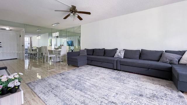 living area with a textured ceiling, ceiling fan, and a wall of windows