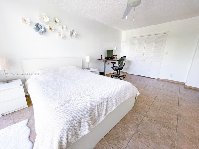 bedroom featuring a textured ceiling, ceiling fan, light tile patterned floors, baseboards, and a closet