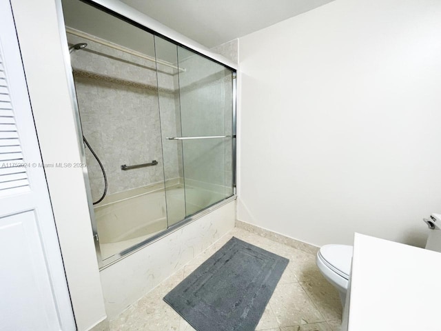 bathroom featuring enclosed tub / shower combo, toilet, and baseboards