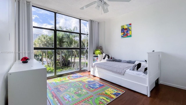 bedroom with a textured ceiling, ceiling fan, dark wood-type flooring, and a wall of windows