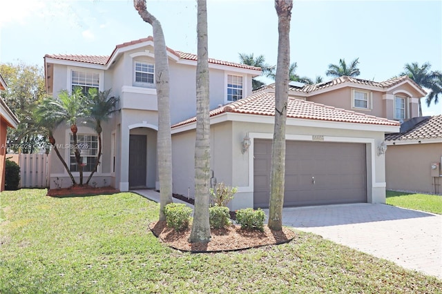 mediterranean / spanish-style home with a front lawn, decorative driveway, an attached garage, and stucco siding