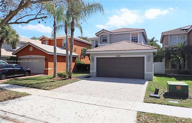 view of front of home with a garage, driveway, a tiled roof, and stucco siding