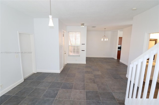 spare room with stairs, dark tile patterned floors, visible vents, and baseboards