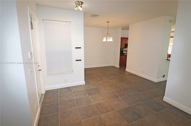 unfurnished dining area with baseboards, visible vents, a notable chandelier, and dark tile patterned flooring