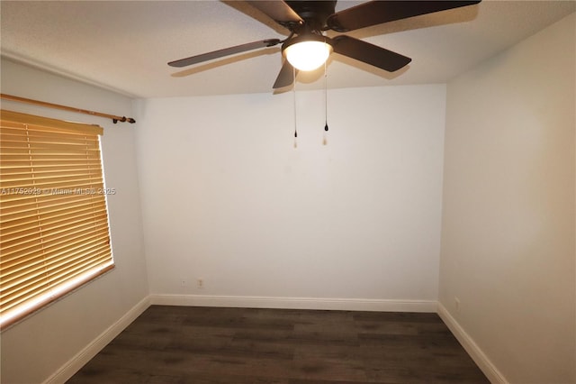 spare room with dark wood-style floors, a ceiling fan, and baseboards