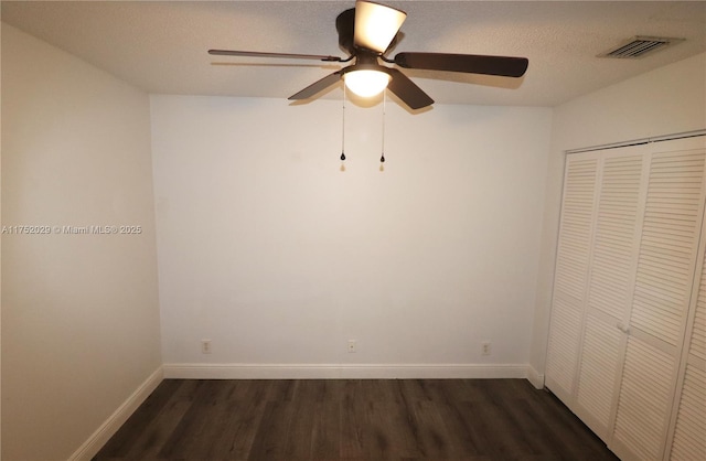 spare room with baseboards, visible vents, a ceiling fan, dark wood-type flooring, and a textured ceiling