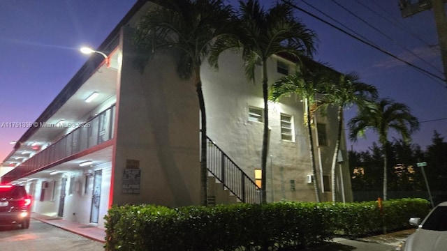 property exterior at night featuring stairs and stucco siding