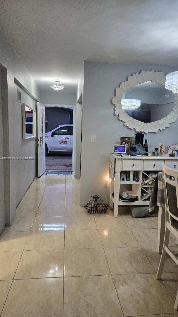 hallway with tile patterned flooring, visible vents, and a textured ceiling