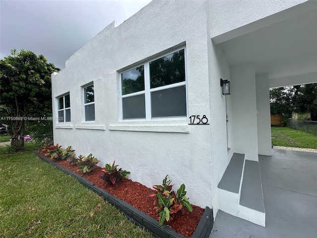 view of side of home featuring stucco siding, a yard, and fence