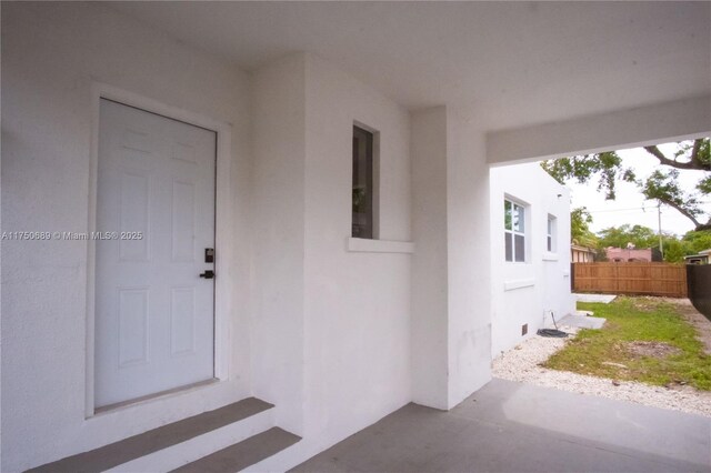 property entrance featuring stucco siding and fence