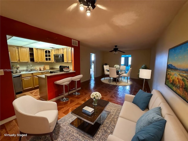 living area featuring baseboards, visible vents, and a ceiling fan