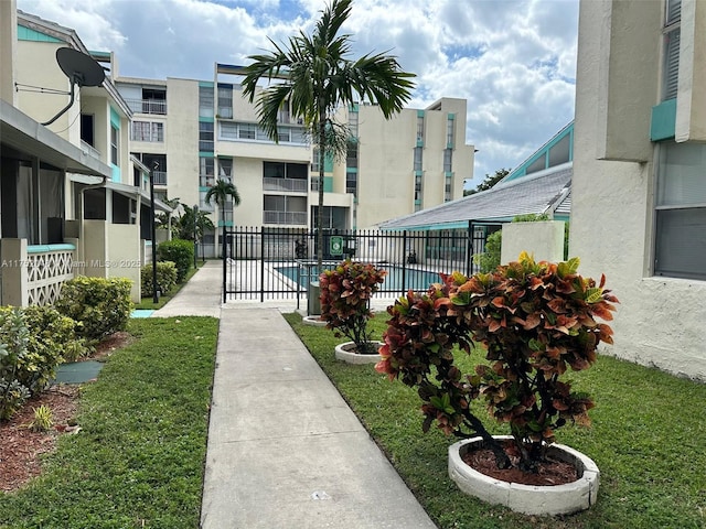 view of property's community with a yard, a swimming pool, and fence