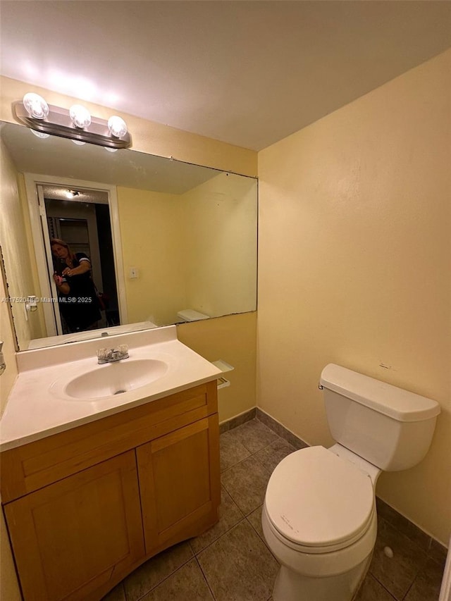 bathroom featuring toilet, tile patterned flooring, vanity, and baseboards