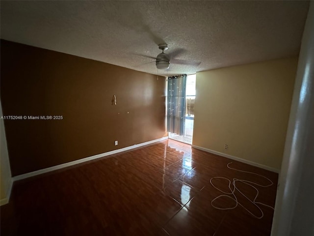 empty room with a textured ceiling, ceiling fan, and baseboards