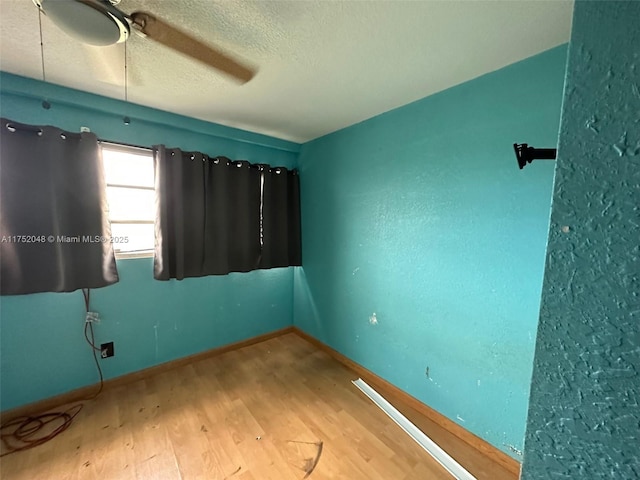 unfurnished bedroom featuring a textured ceiling, wood finished floors, a ceiling fan, and baseboards