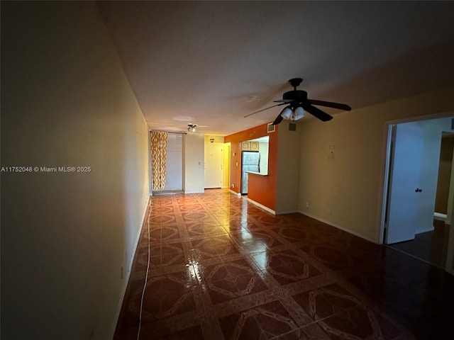 empty room featuring ceiling fan and baseboards