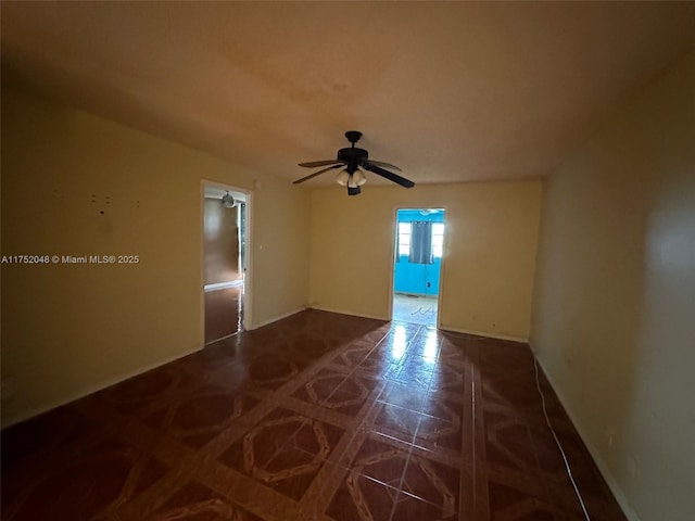 empty room featuring ceiling fan and baseboards