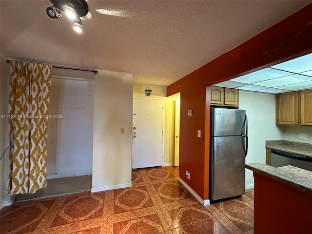 kitchen featuring a textured ceiling, dark floors, appliances with stainless steel finishes, and baseboards