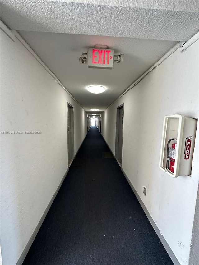 corridor featuring a textured ceiling and carpet floors