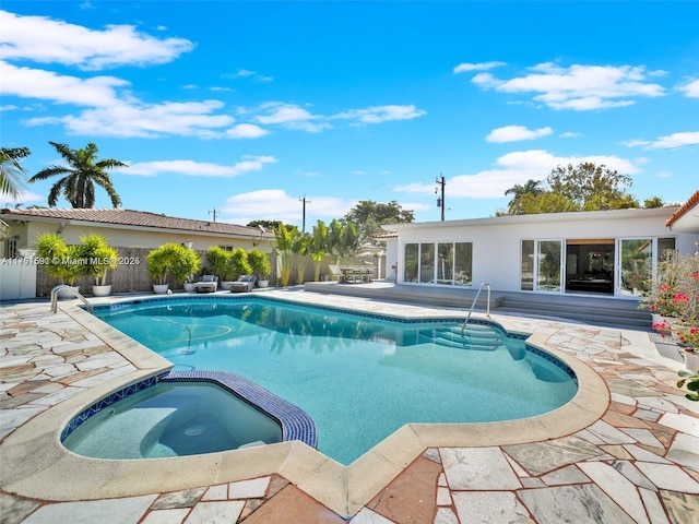 view of pool featuring a pool with connected hot tub and fence