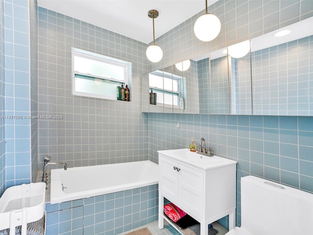 bathroom with a relaxing tiled tub, tile walls, and vanity