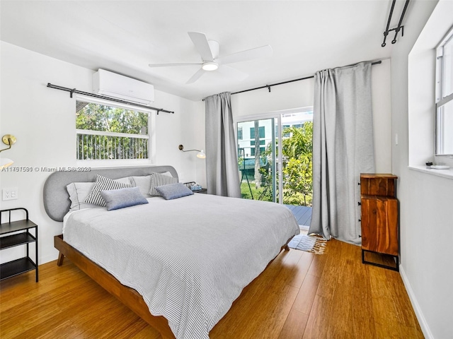 bedroom featuring a ceiling fan, baseboards, an AC wall unit, hardwood / wood-style floors, and track lighting