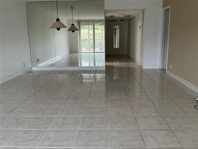 empty room featuring baseboards and light tile patterned floors