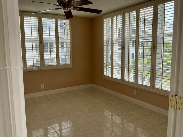 unfurnished room featuring ceiling fan, light tile patterned flooring, and baseboards