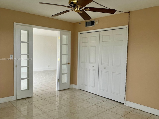 unfurnished bedroom with ceiling fan, light tile patterned floors, visible vents, baseboards, and a closet