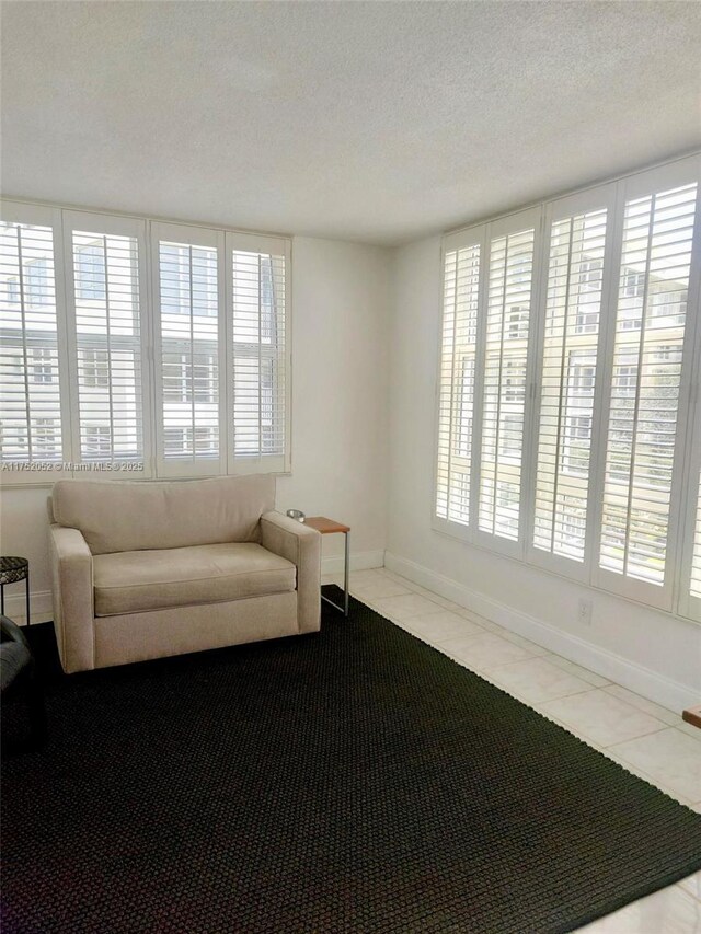 2650 S Course Dr Unit 410, Pompano Beach, FL 33069 - living area featuring healthy amount of natural light, a textured ceiling, baseboards, and tile patterned flooring