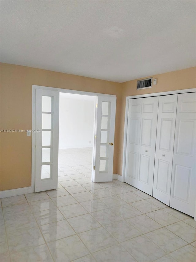 2650 S Course Dr Unit 410, Pompano Beach, FL 33069 - unfurnished bedroom featuring french doors, baseboards, a closet, and a textured ceiling