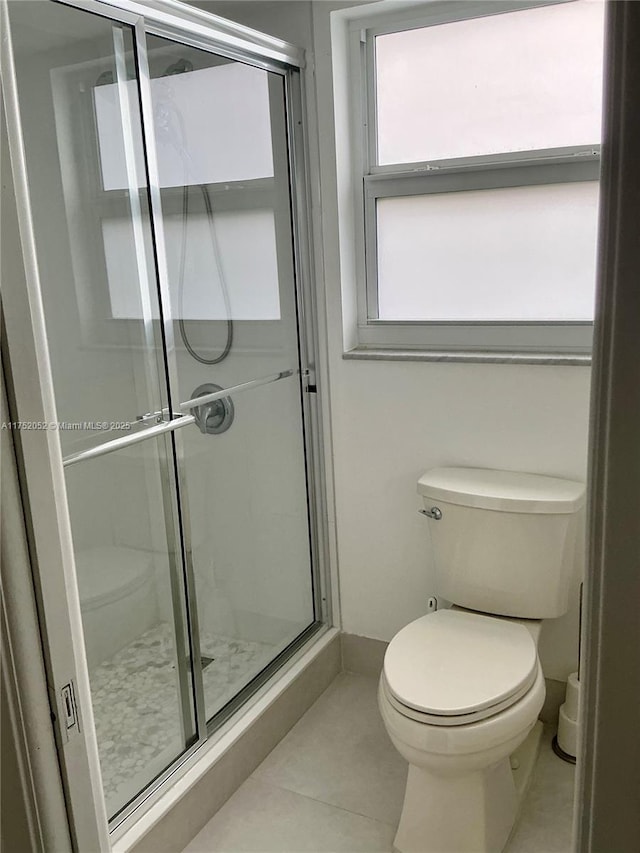 bathroom with a stall shower, tile patterned flooring, and toilet