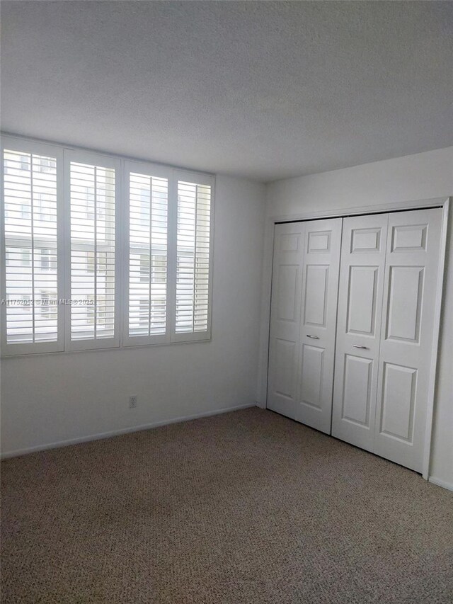 2650 S Course Dr Unit 410, Pompano Beach, FL 33069 - unfurnished bedroom with carpet flooring, a textured ceiling, a closet, and baseboards