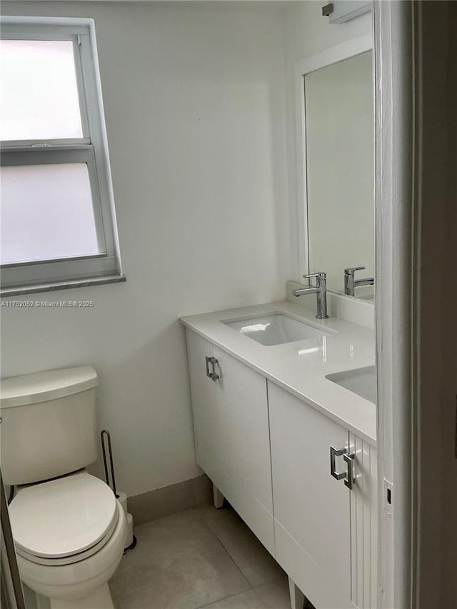 bathroom with double vanity, tile patterned flooring, a sink, and toilet