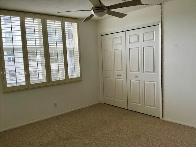 unfurnished bedroom featuring carpet, baseboards, ceiling fan, and a closet