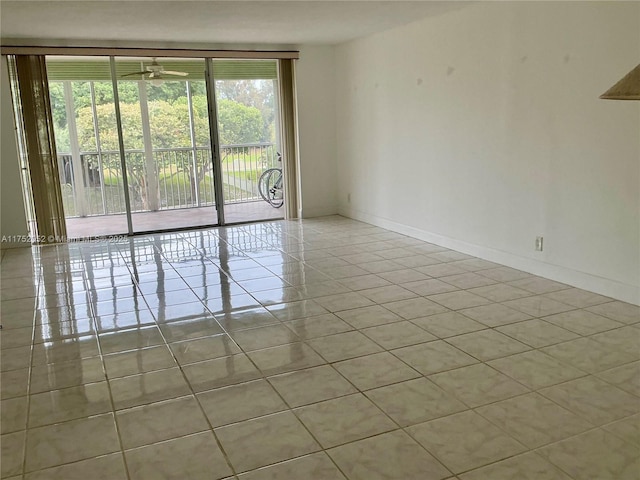 empty room with light tile patterned flooring, a ceiling fan, and baseboards